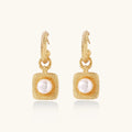 Gold earrings with pearl centers on a white background