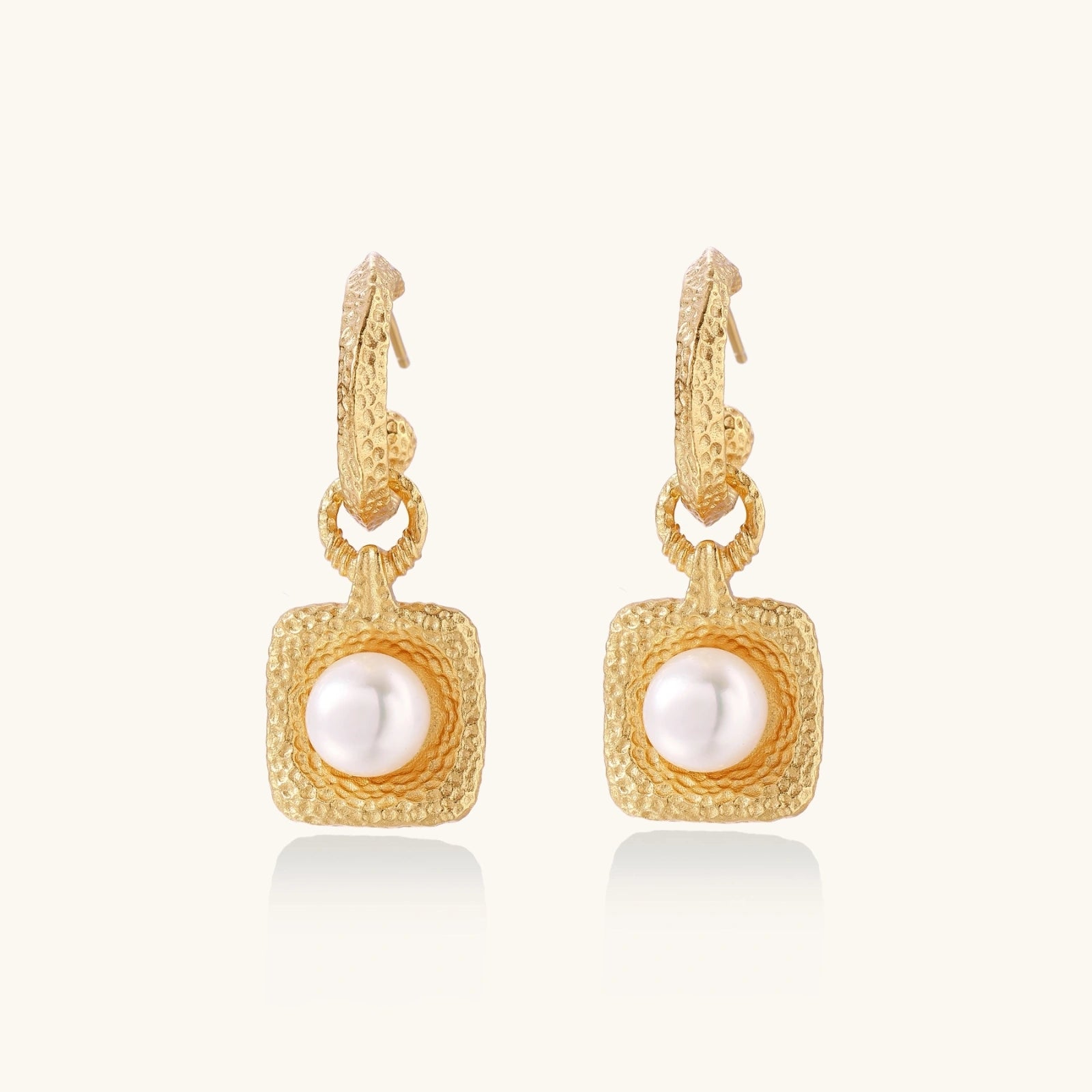 Gold earrings with pearl centers on a white background