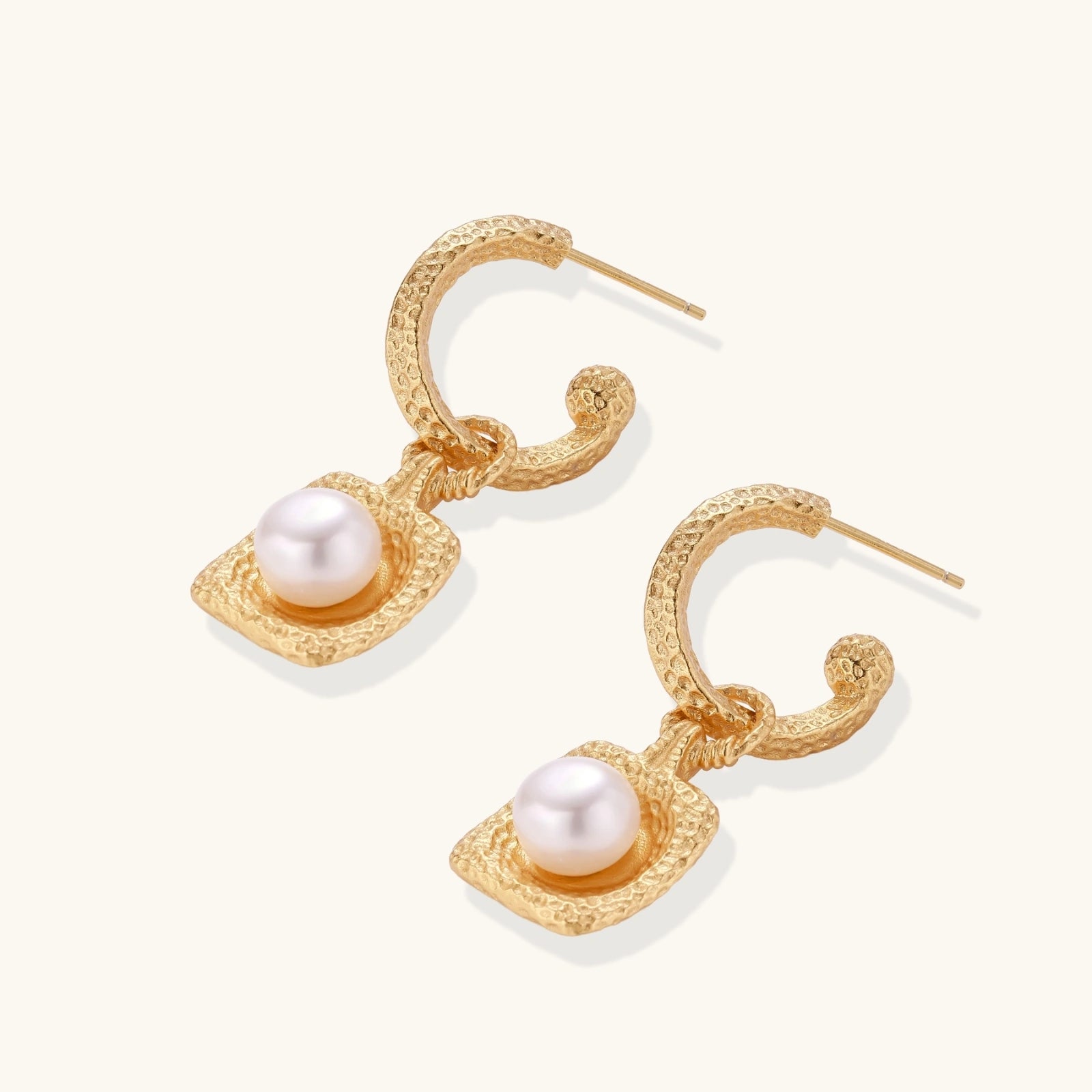 Gold earrings with pearl drops on a white background