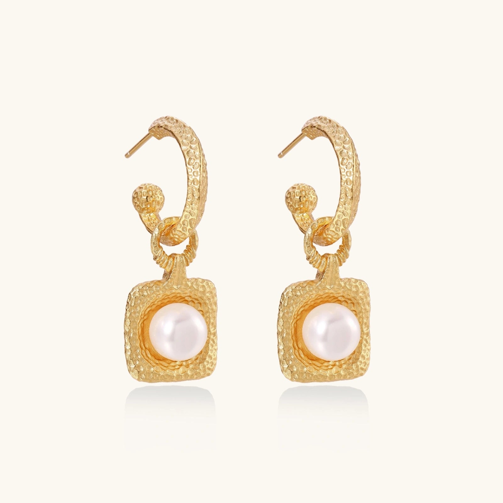 Gold earrings with pearl centers on a white background