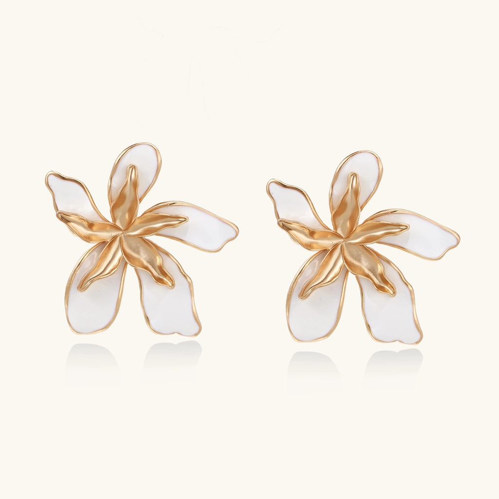 Pair of gold and white flower-shaped earrings on a white background