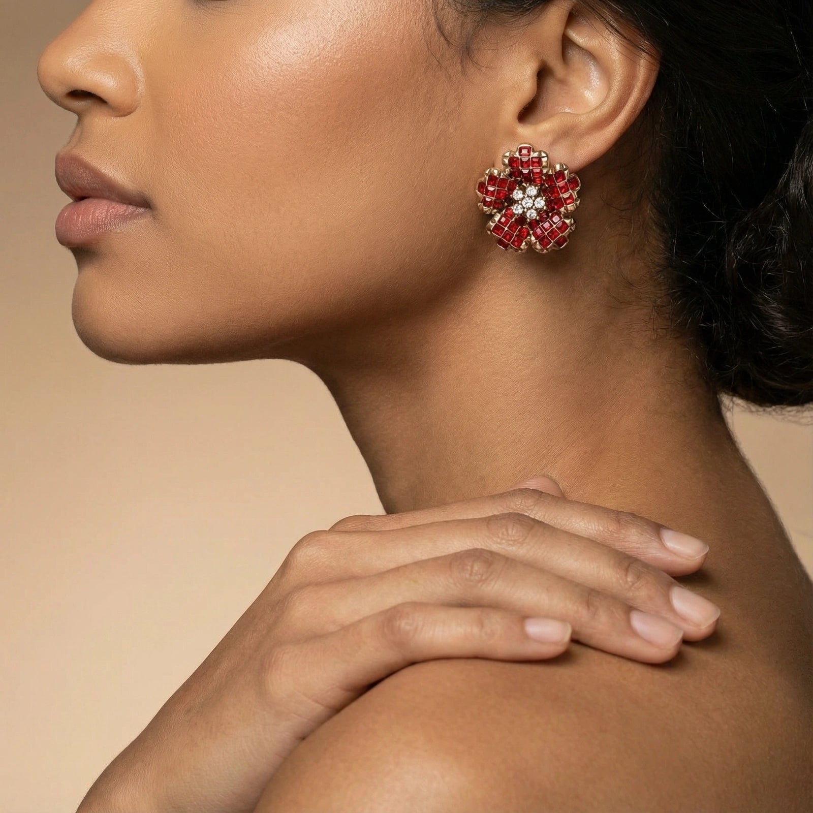 Close-up of a woman wearing red floral earrings with a neutral background