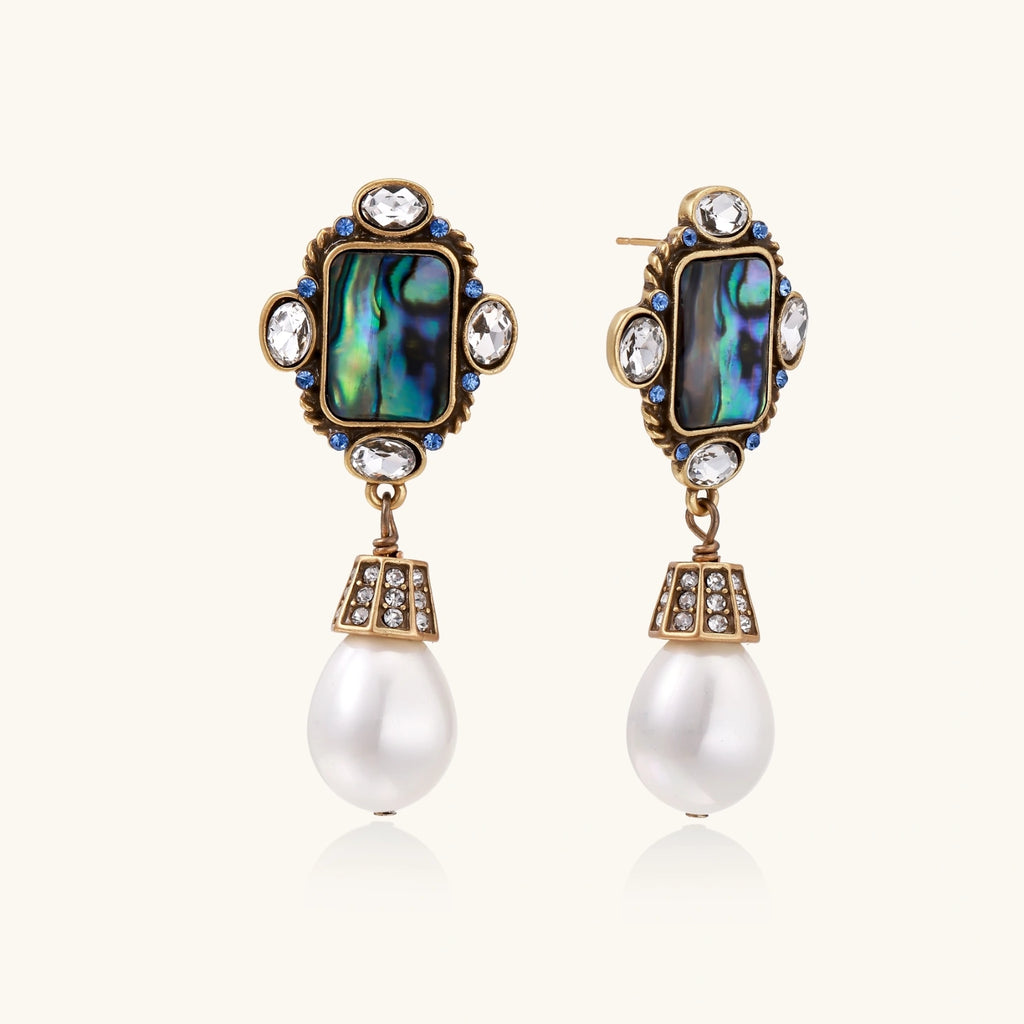 Pair of ornate earrings with gemstones and pearls on a white background