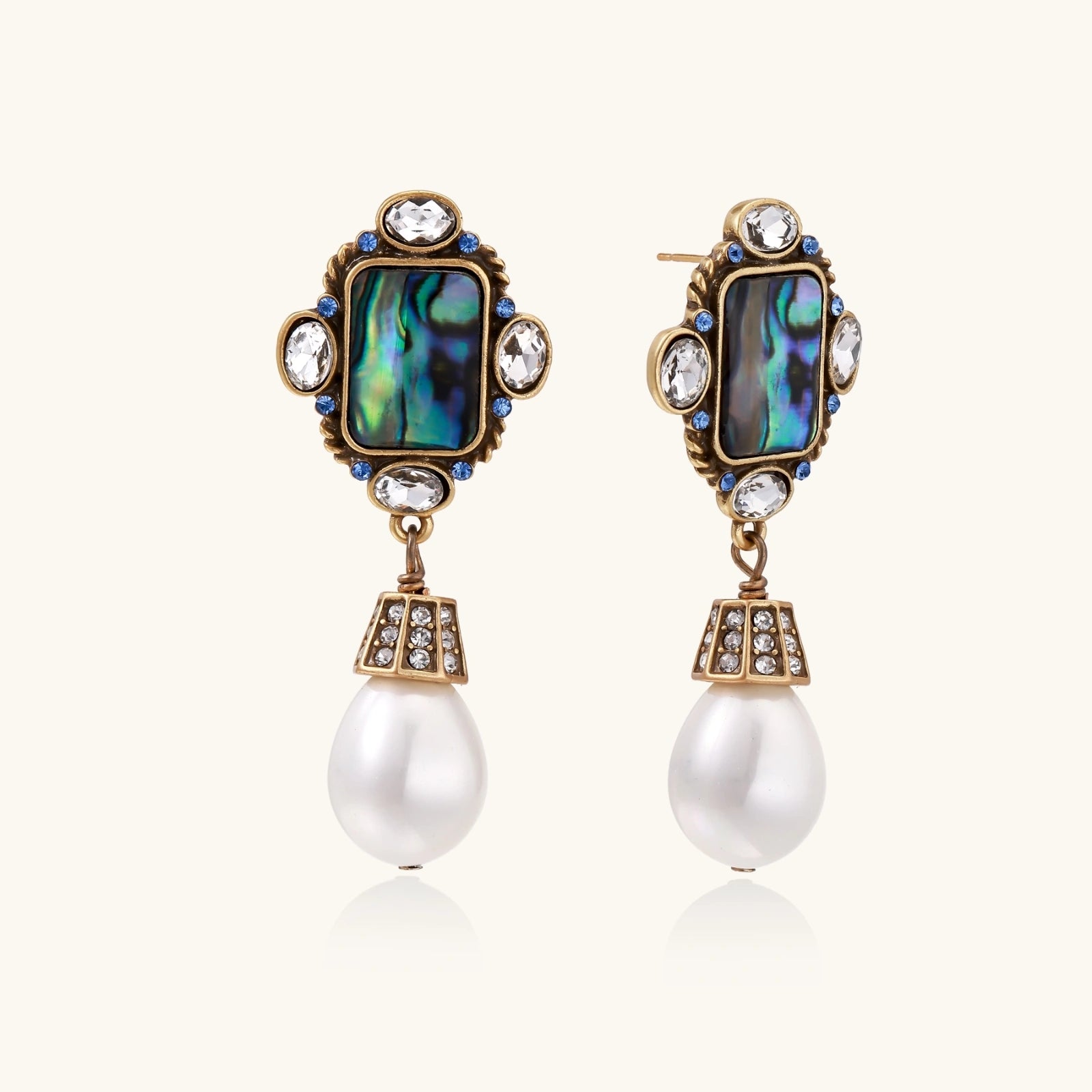 Pair of ornate earrings with gemstones and pearls on a white background