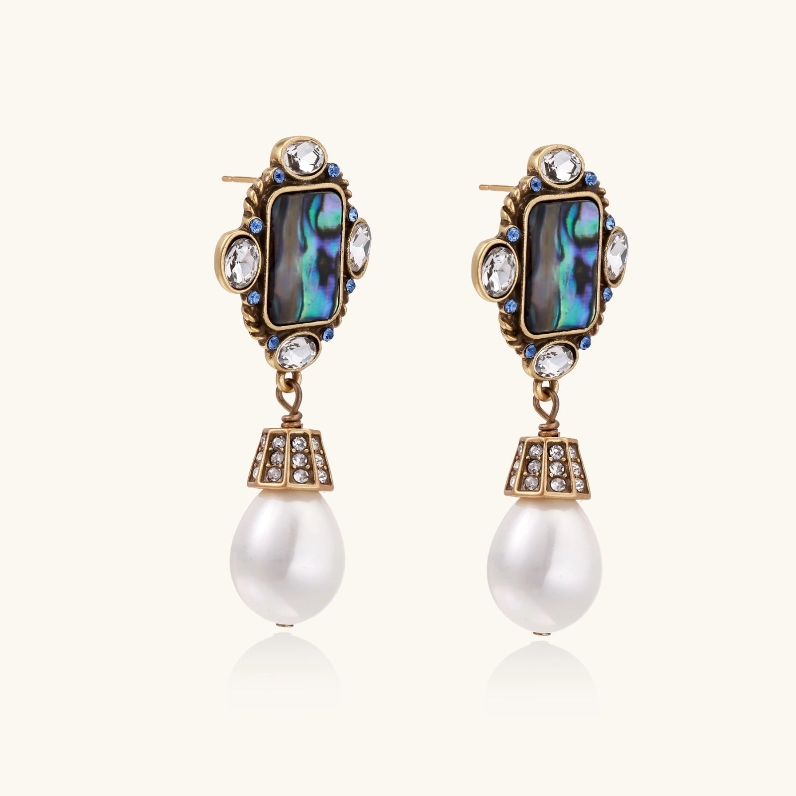 Pair of ornate earrings with pearl drops on a white background