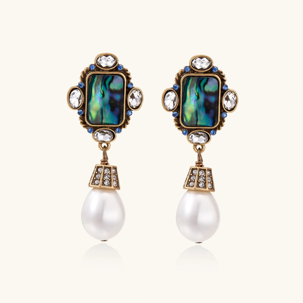 Pair of ornate earrings with gemstones and pearls on a white background