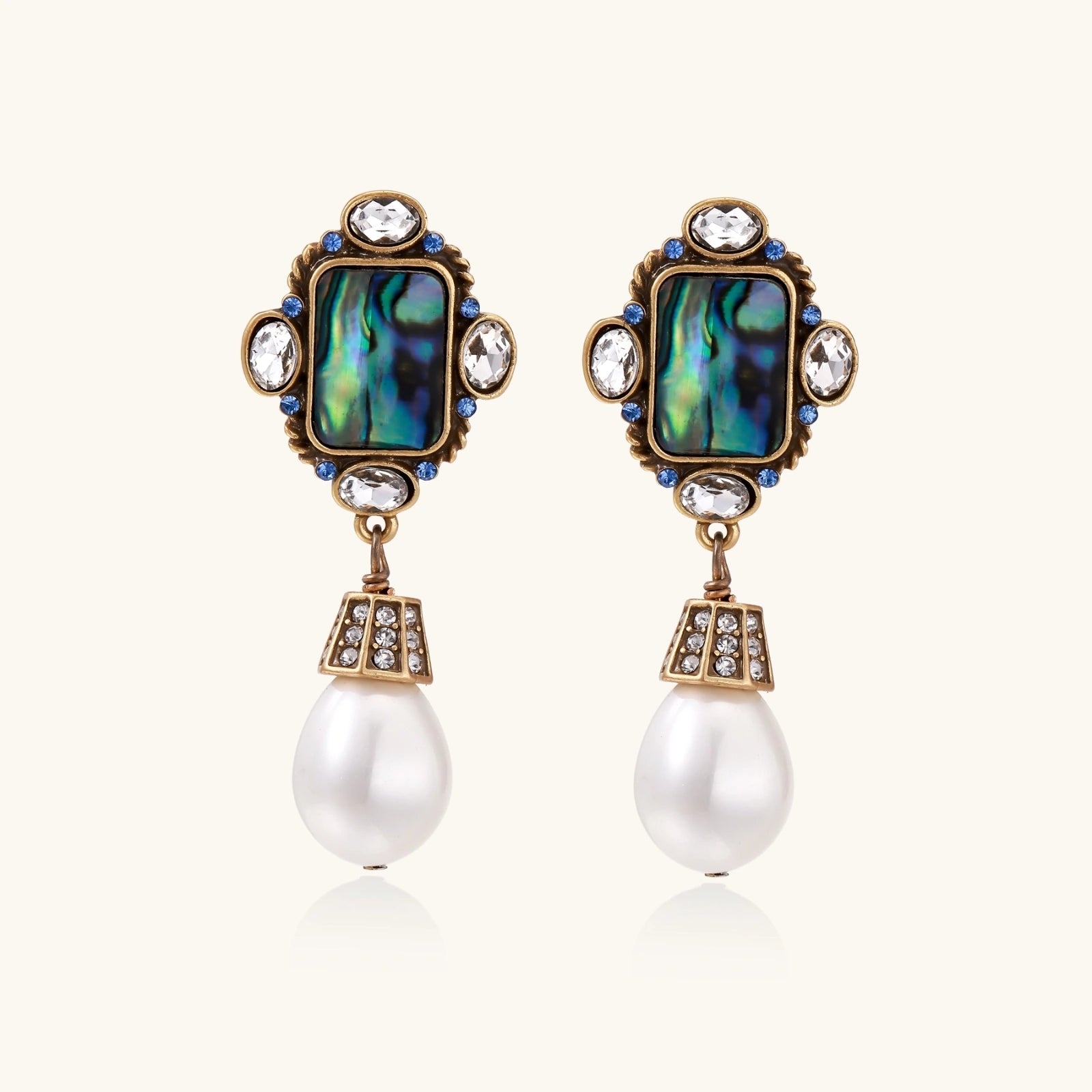 Pair of ornate earrings with gemstones and pearls on a white background