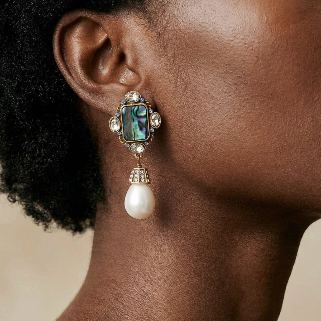 Close-up of a woman wearing an elegant earring with a pearl and abalone shell design.