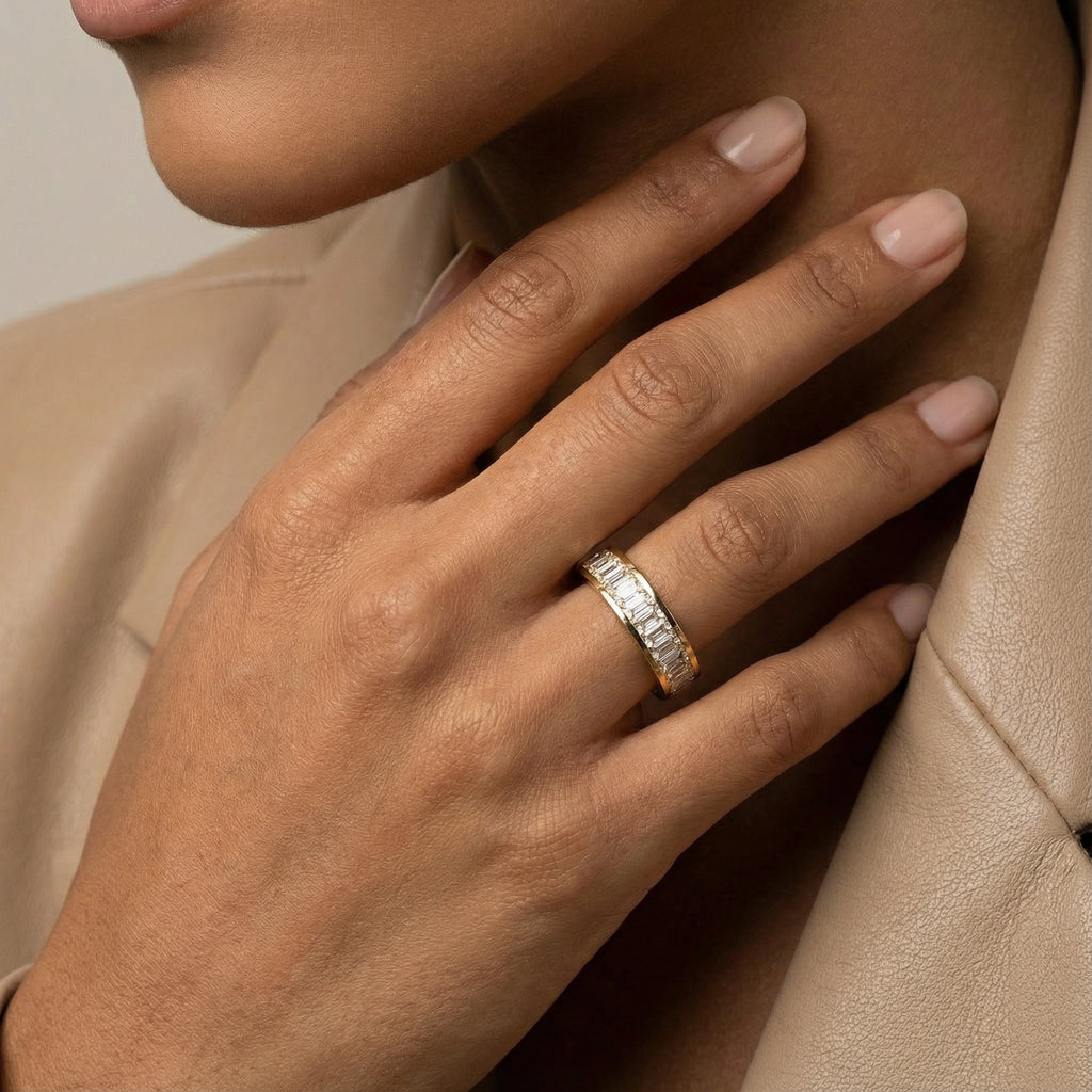 Close-up of a hand wearing a diamond ring on a neutral background