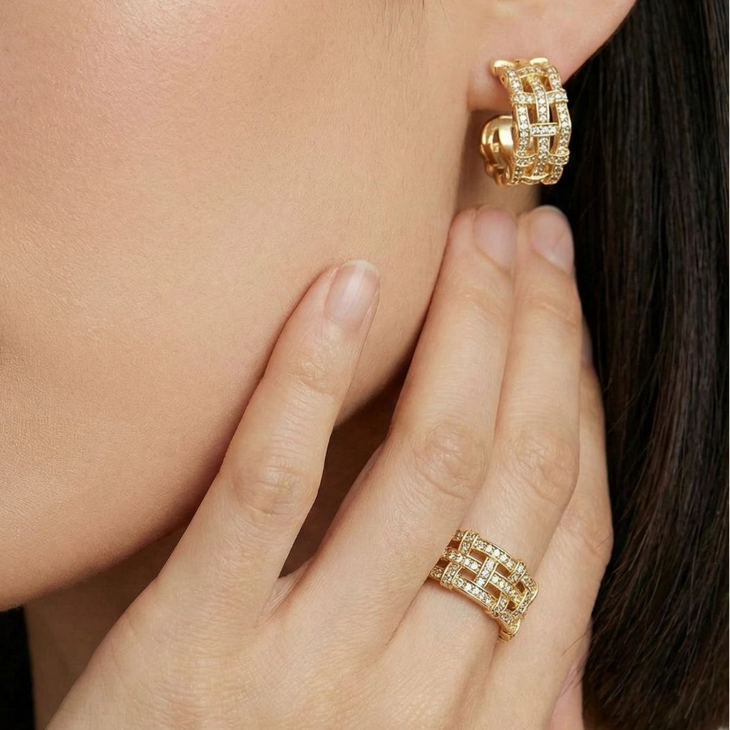 Close-up of a woman wearing gold hoop earrings and a ring, with a soft focus on her face.