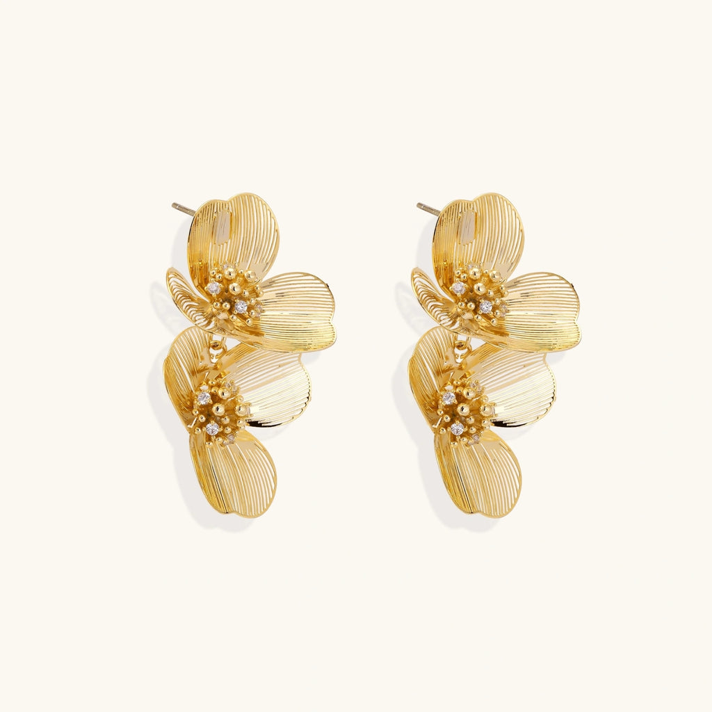 Pair of gold floral earrings on a white background
