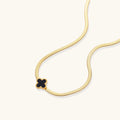 Gold necklace with a black clover pendant on a white background