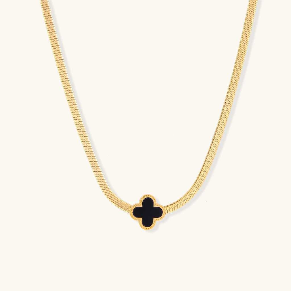 Gold necklace with a black clover-shaped pendant on a white background
