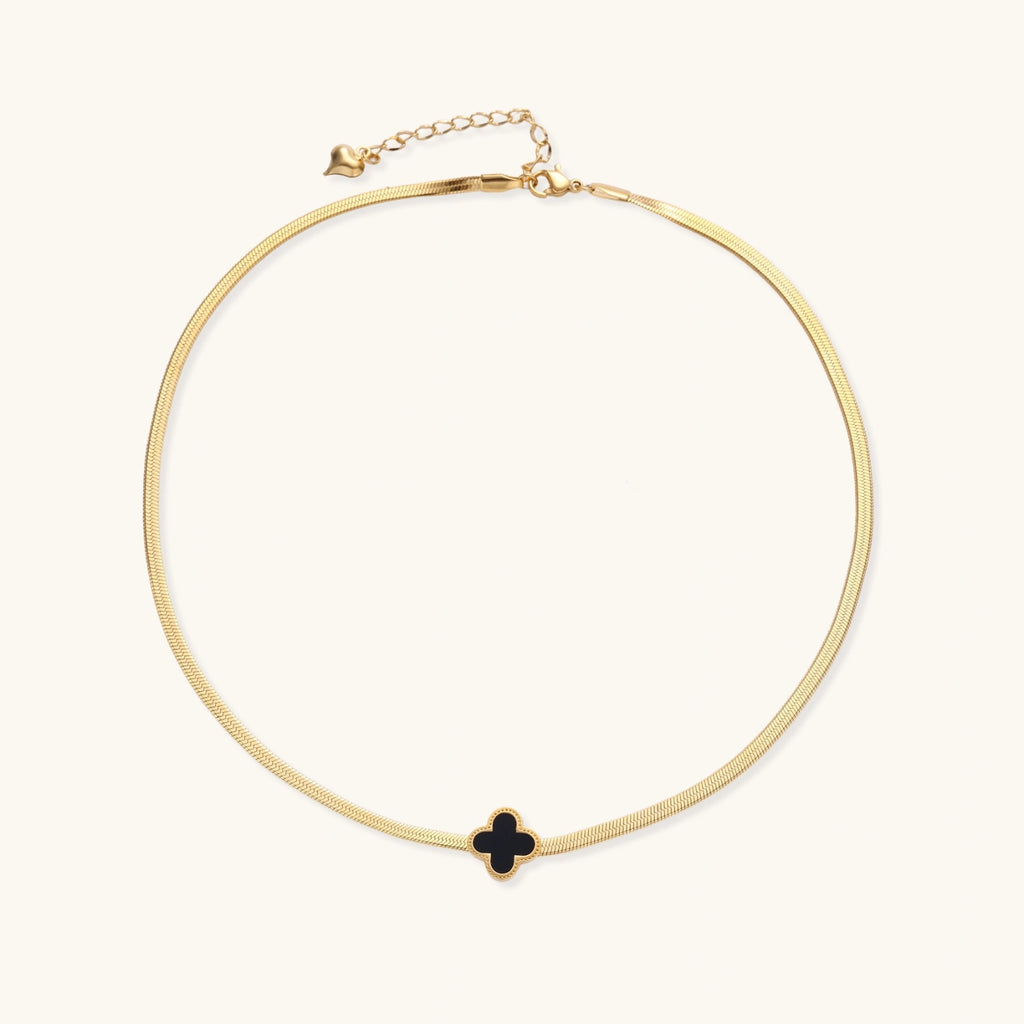 Gold necklace with a black clover pendant on a white background