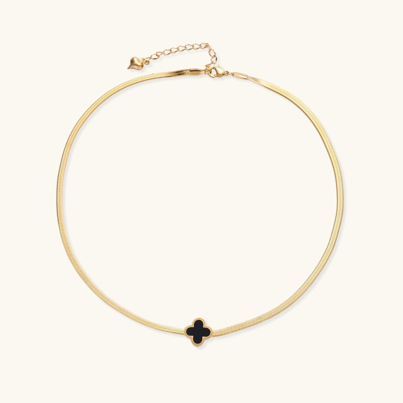 Gold necklace with a black clover pendant on a white background
