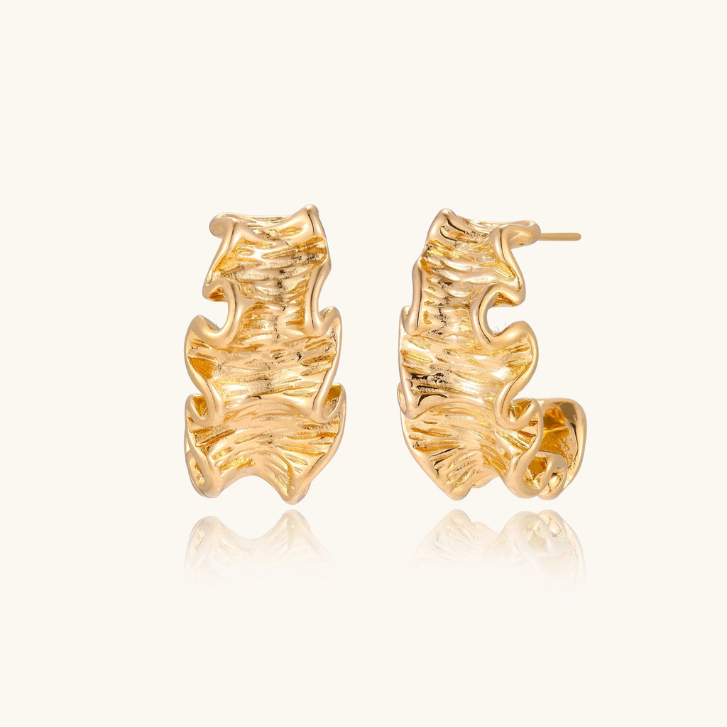 Gold leaf-shaped earrings on a white background