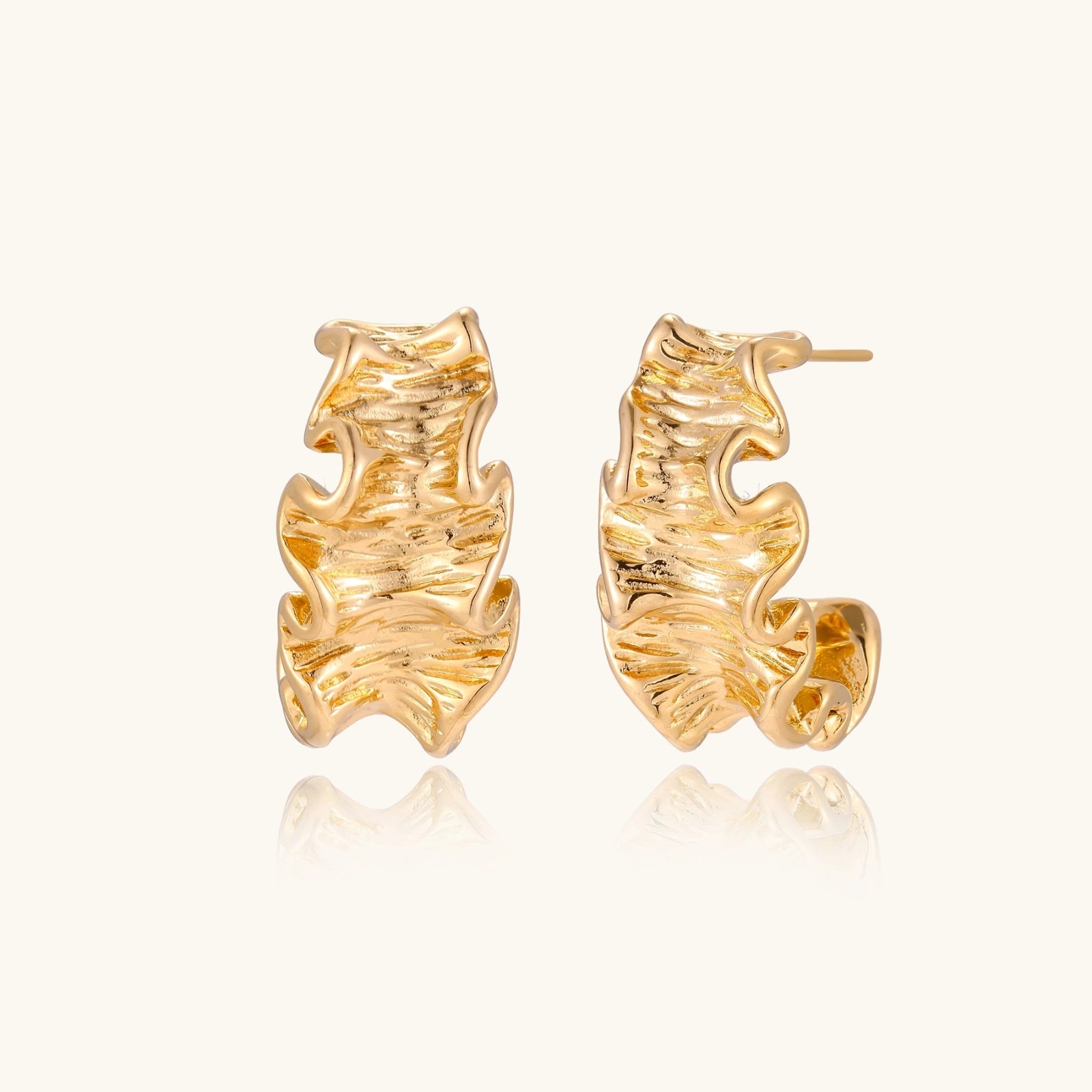 Gold leaf-shaped earrings on a white background