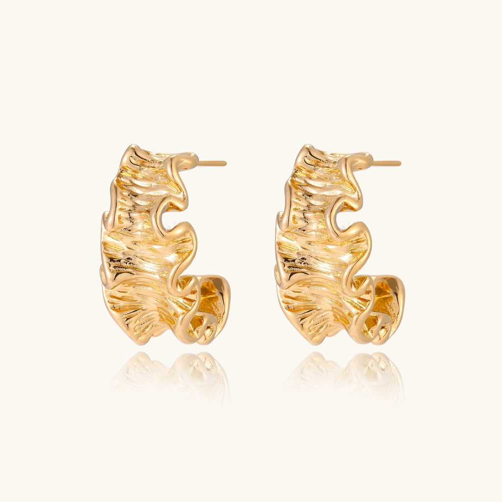 Gold leaf-shaped earrings on a white background