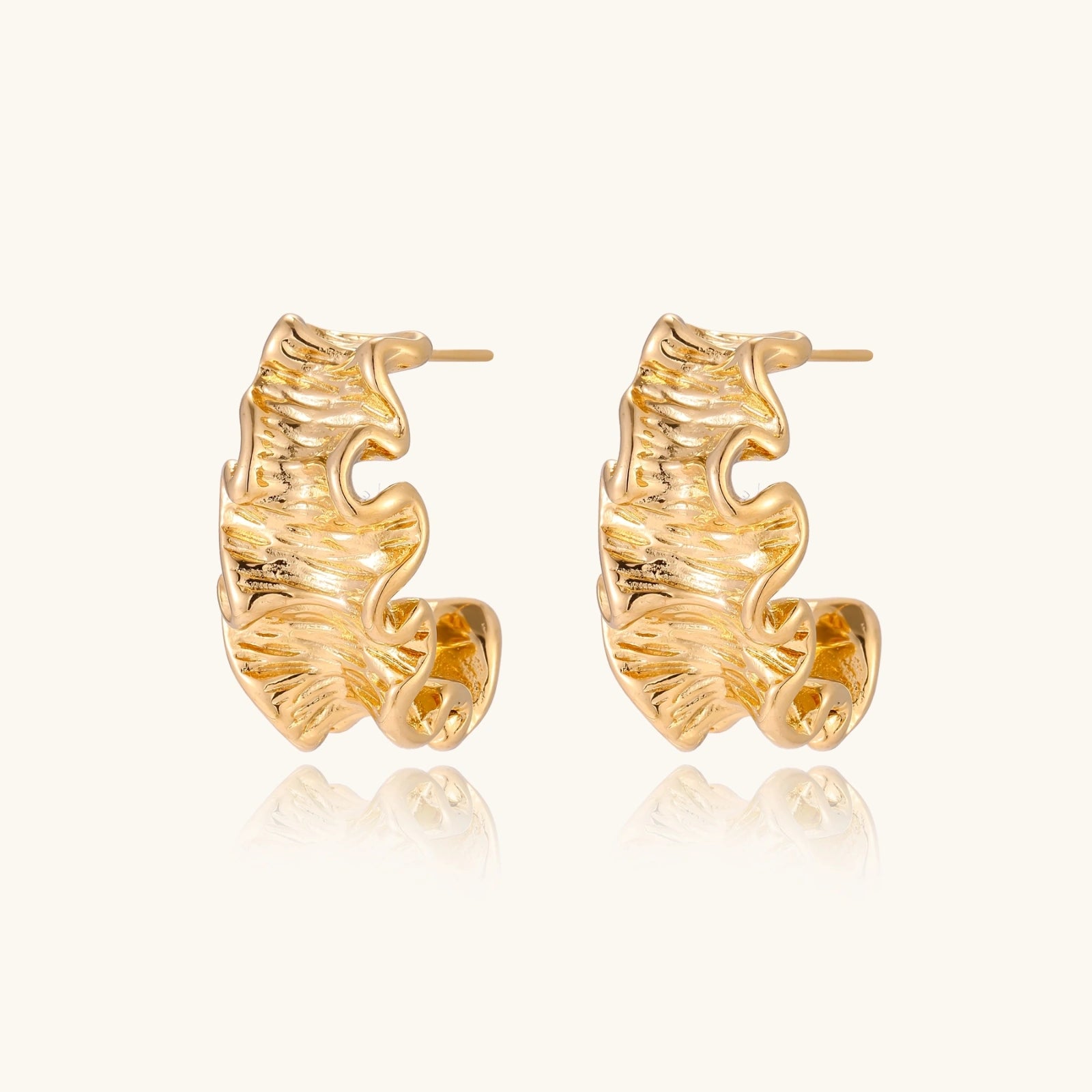 Gold leaf-shaped earrings on a white background