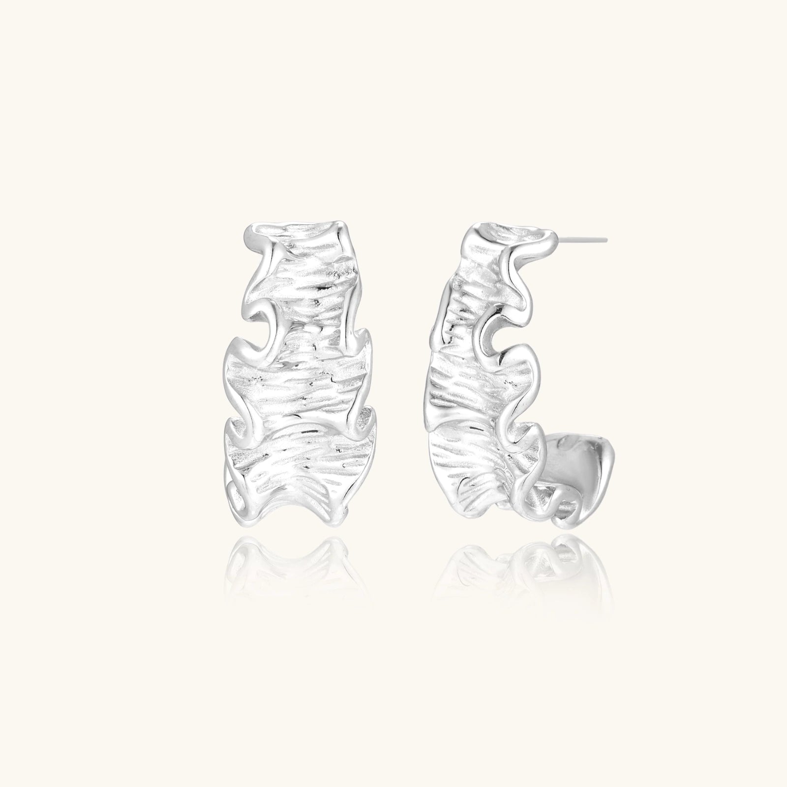 Silver earrings with wavy design on a white background