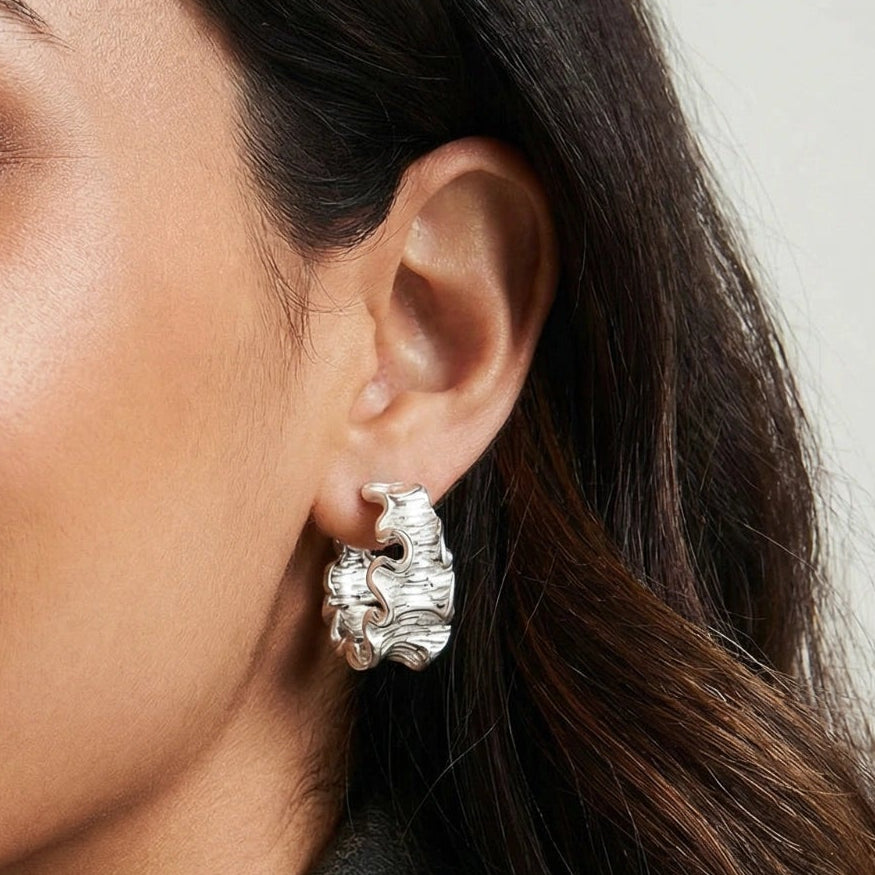 Close-up of a woman wearing a silver earring with a neutral background
