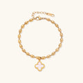 Gold bracelet with a pink clover charm on a white background