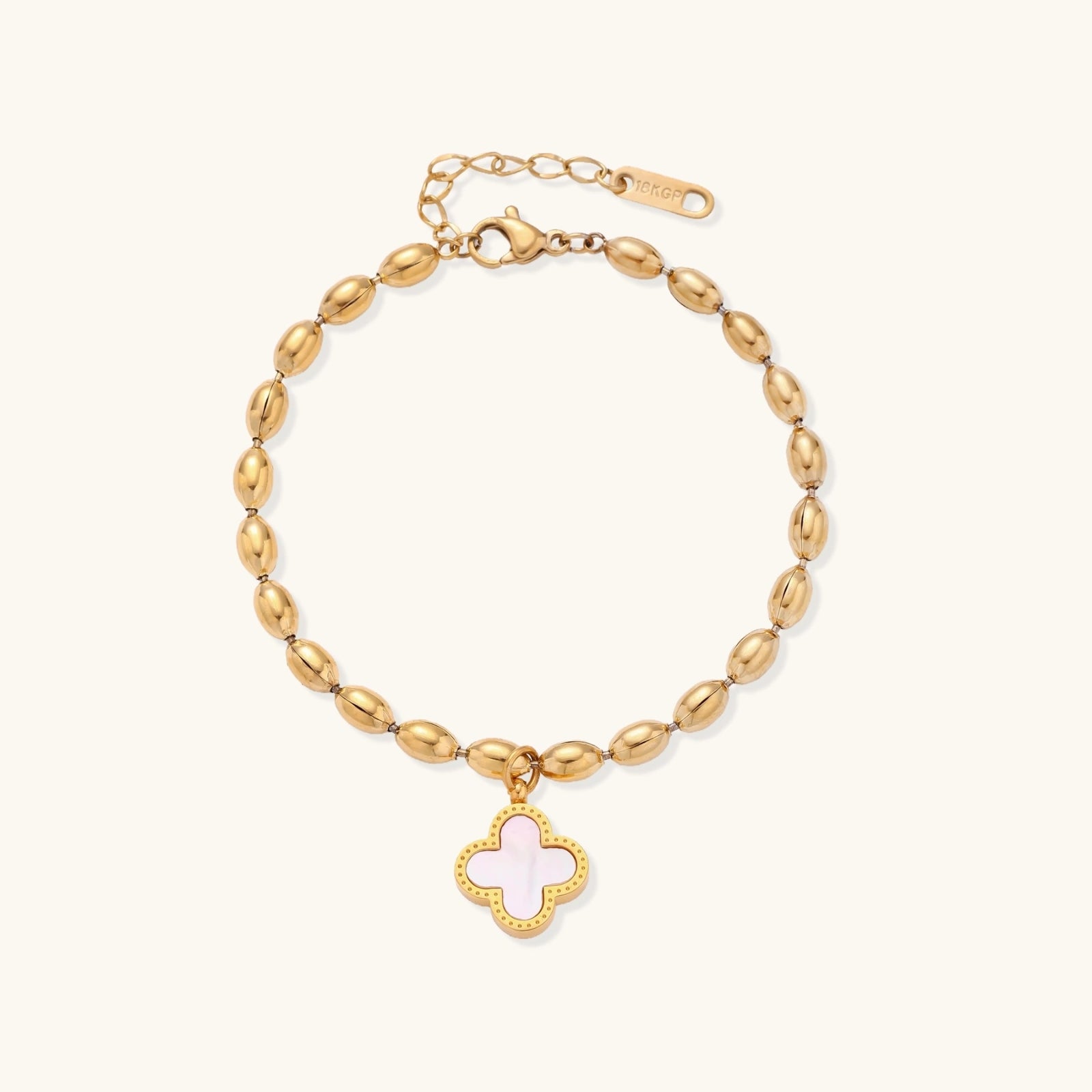 Gold bracelet with a pink clover charm on a white background