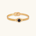 Gold bracelet with a black center stone on a white background