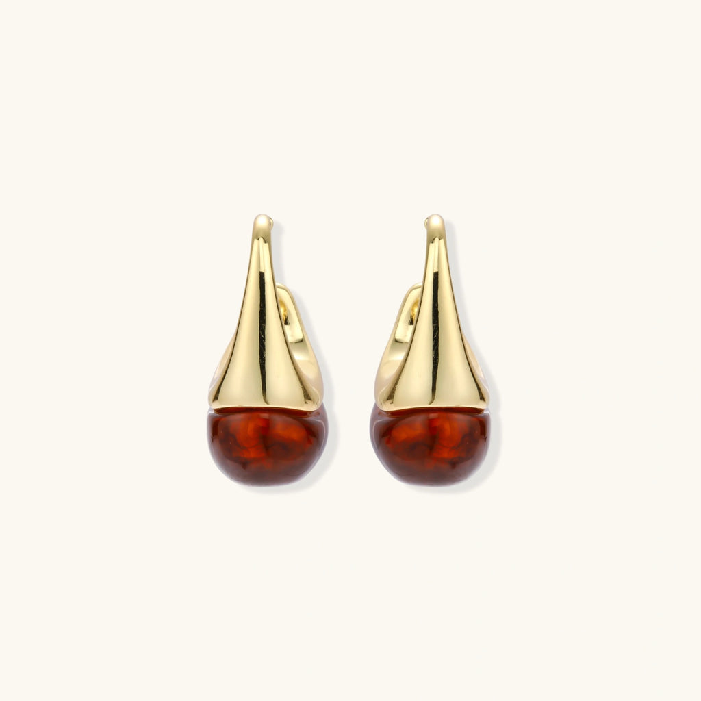 Gold earrings with amber drops on a white background