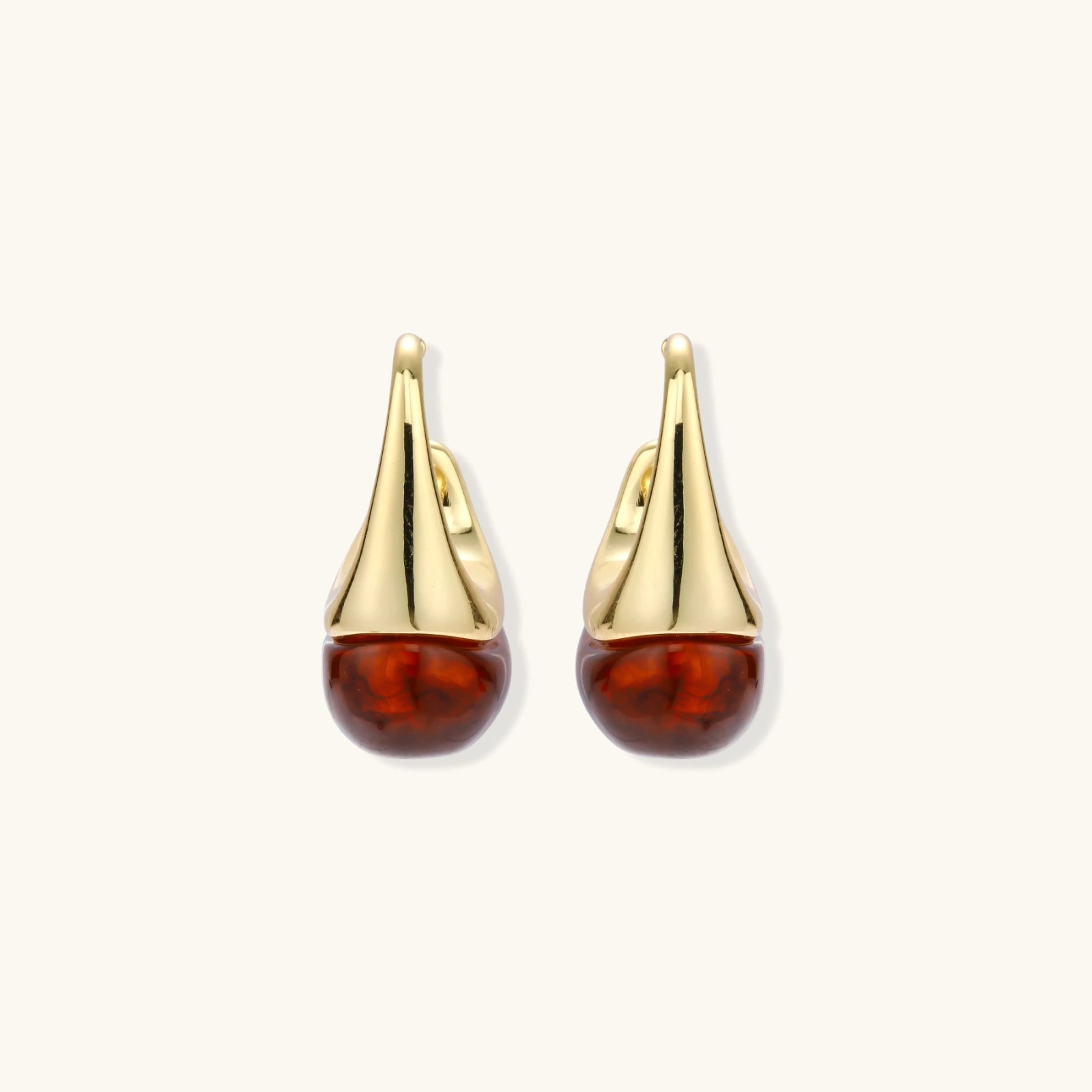 Gold earrings with amber drops on a white background