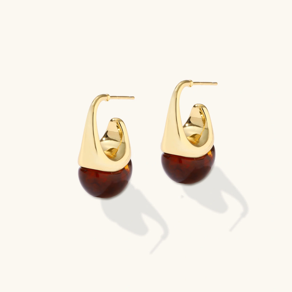 Gold hoop earrings with amber-colored drops on a white background