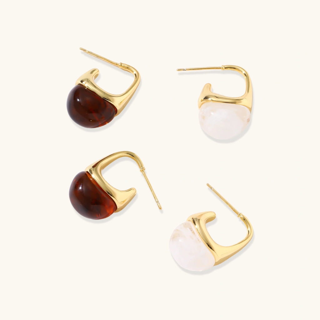 Gold hoop earrings with amber and white stone accents on a white background