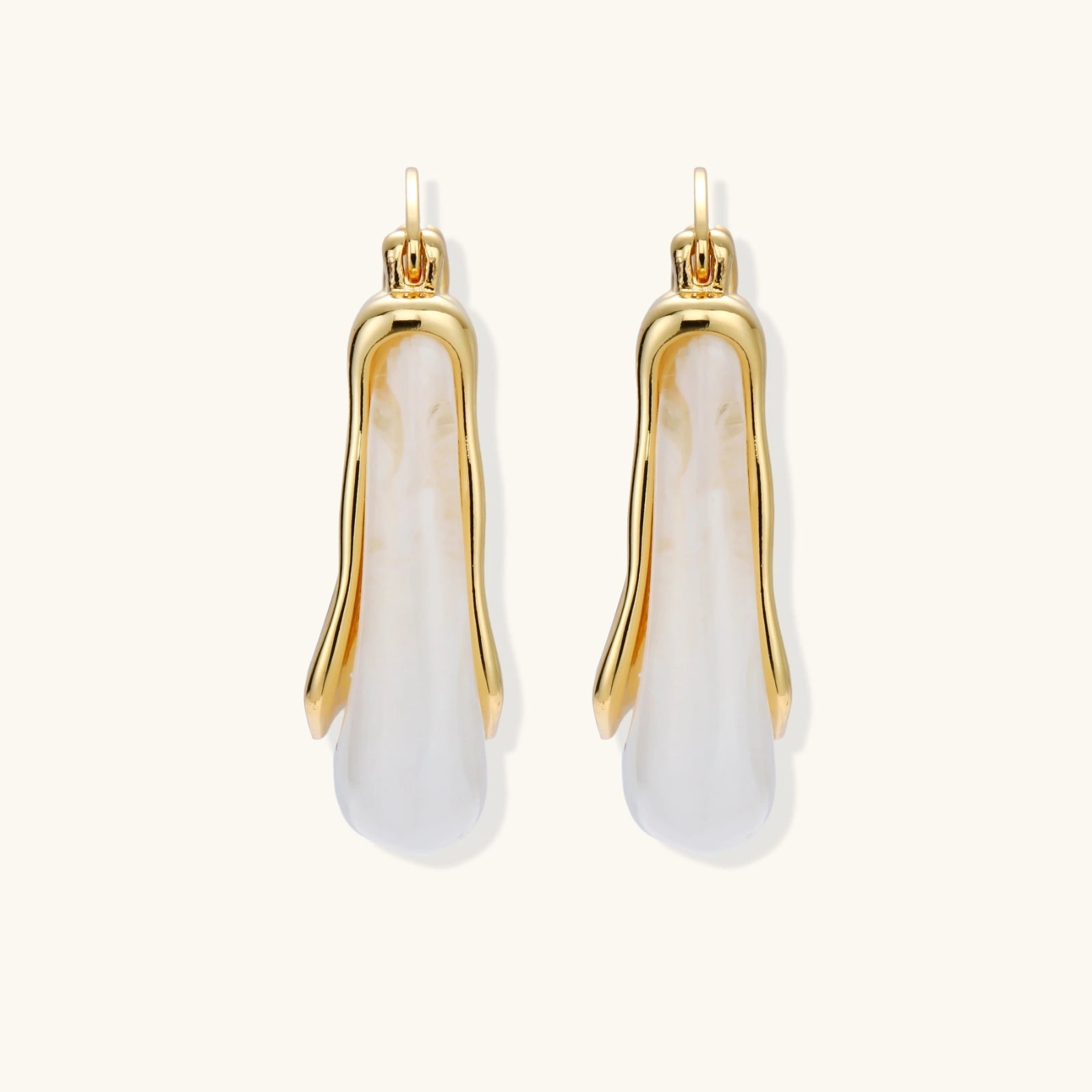 Gold and white earrings on a white background