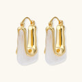 Gold hoop earrings with white stones on a white background