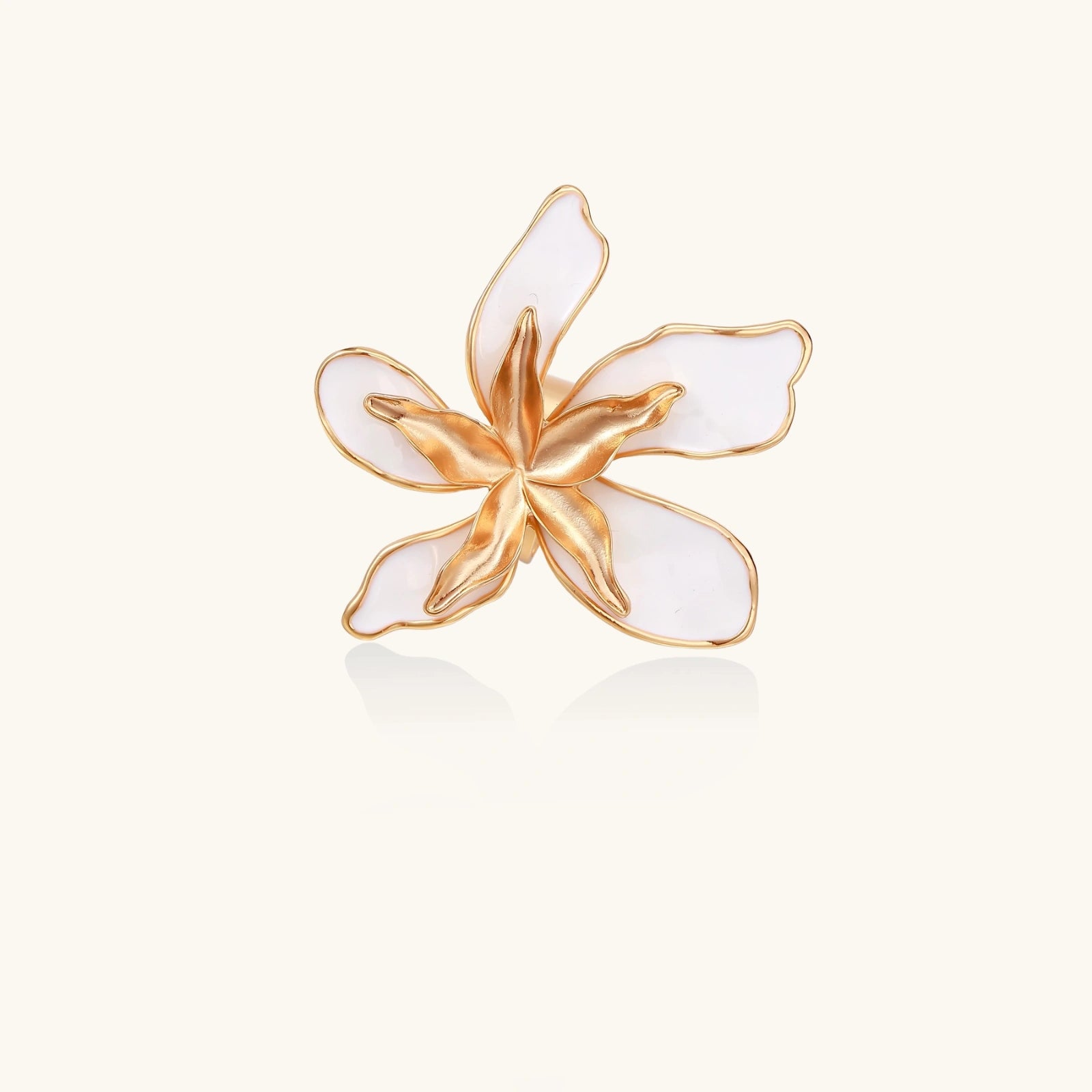 Gold and white flower-shaped brooch on a light beige background