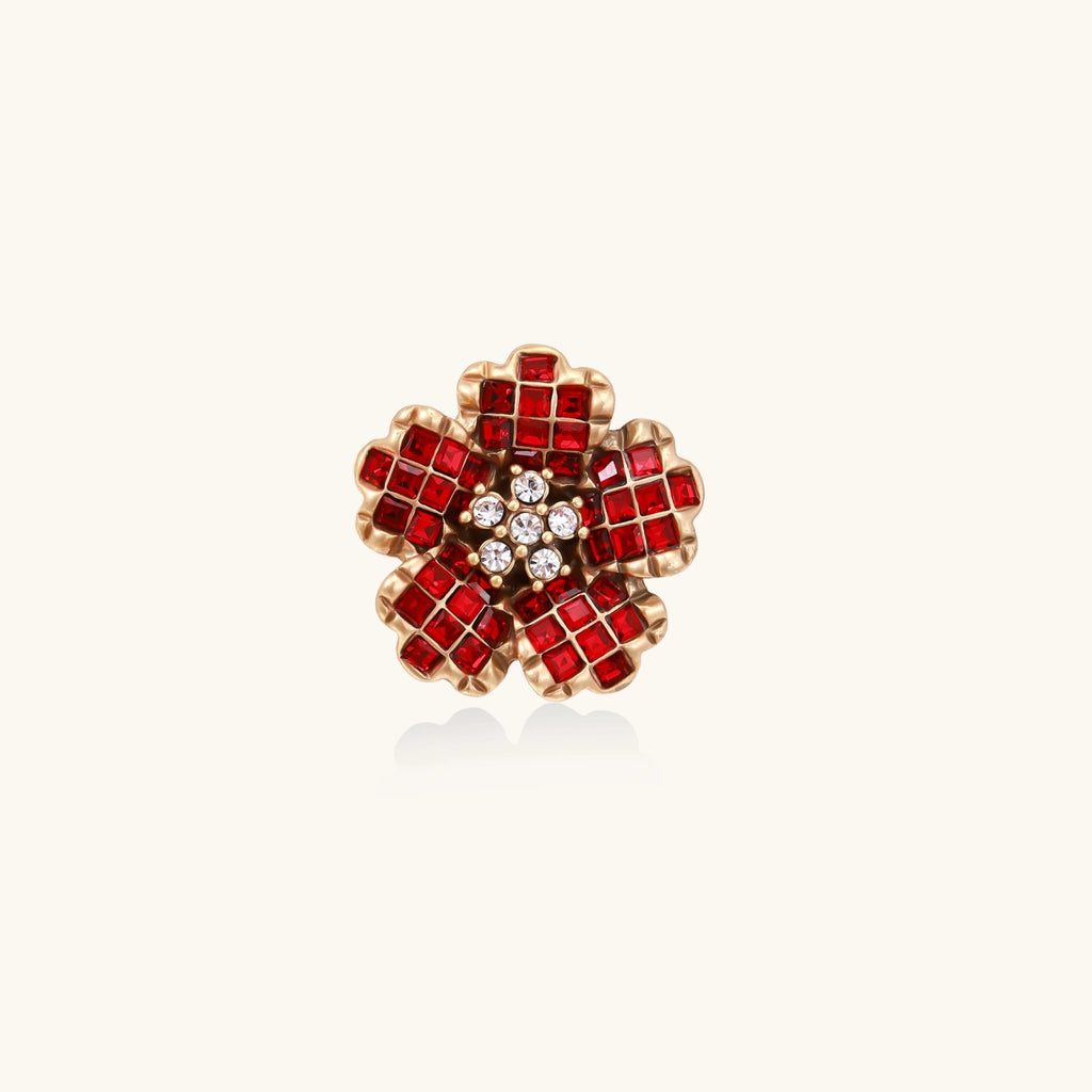 Red flower-shaped crystal statement ring with gold accents on a white background