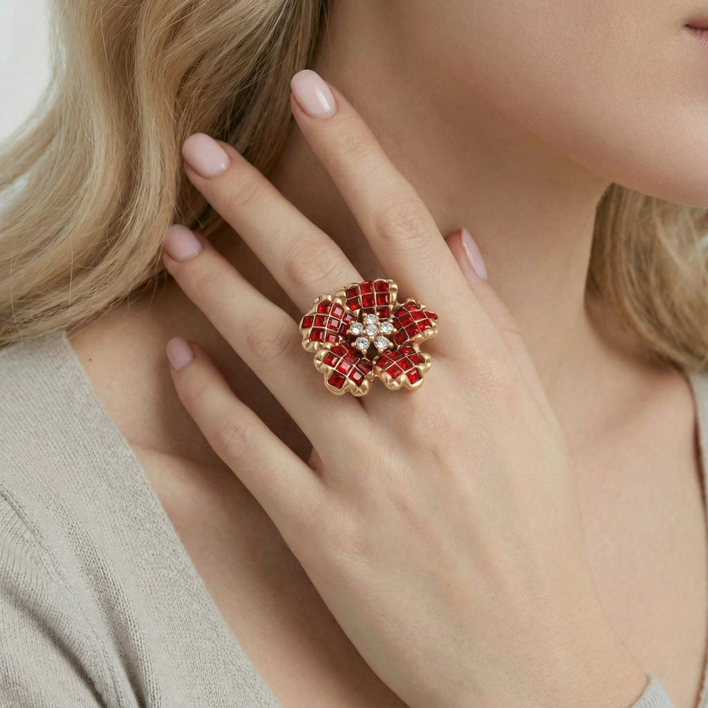 Close-up of a hand wearing a red floral ring with gold accents.