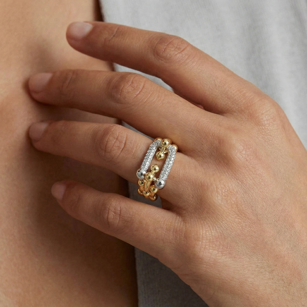 Close-up of a hand wearing a gold ring with cz center on a neutral background