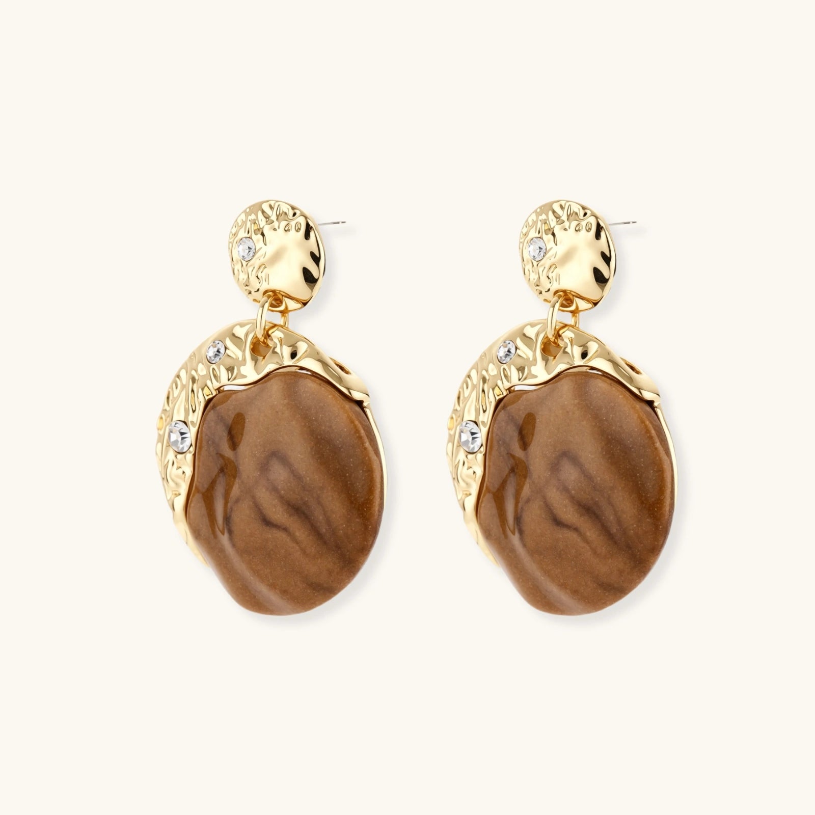Gold earrings with brown stone drops on a white background