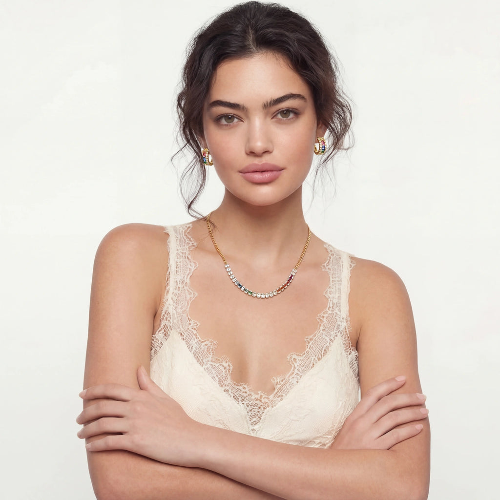 Woman wearing a rainbow zirconia necklace and earring set in lace top with a plain background