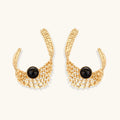Pair of gold hoop earrings with black gemstones on a white background
