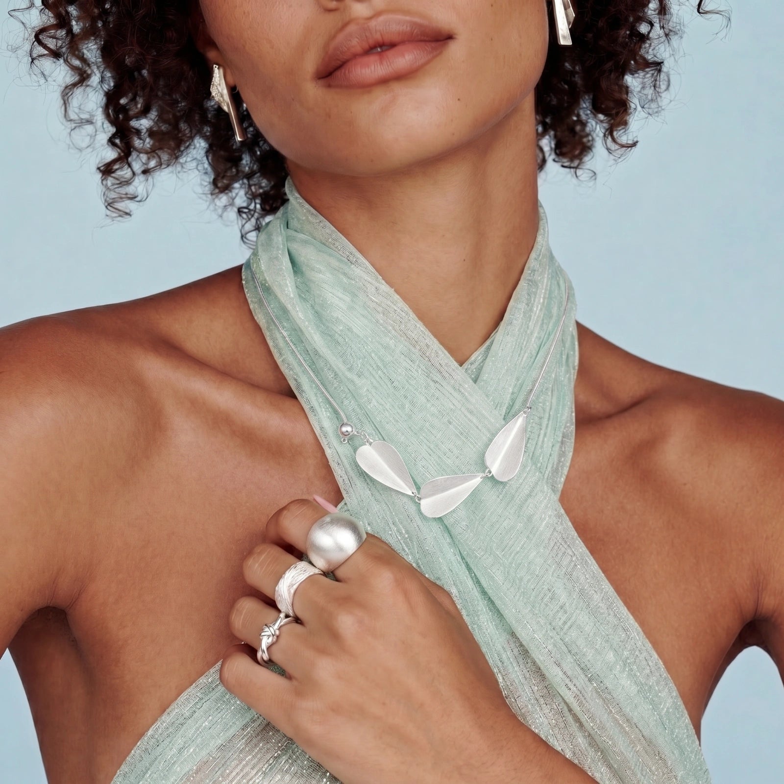 Woman wearing Sterling Silver Necklace with leaf-shaped pendants and adjustable length and silver rings