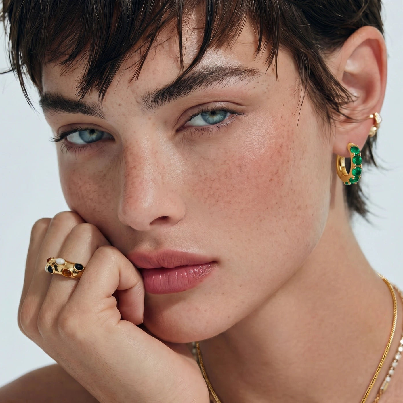 Close-up of a woman wearing gold jewelry with a neutral background