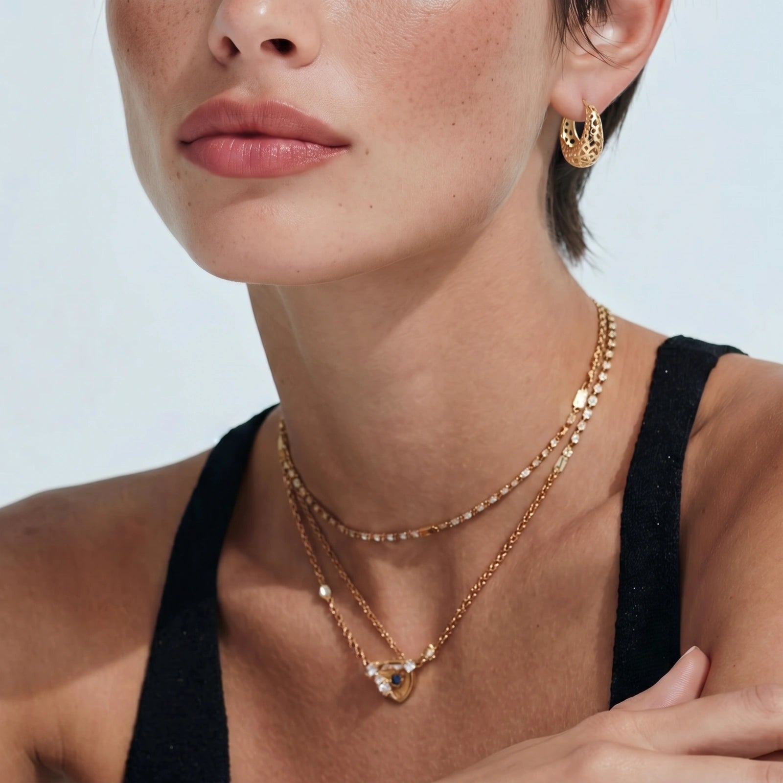Close-up of a person wearing gold necklaces and earrings on a white background
