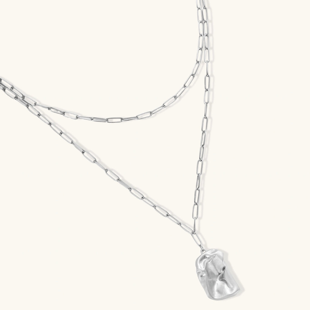 Silver necklace with a clear pendant on a white background