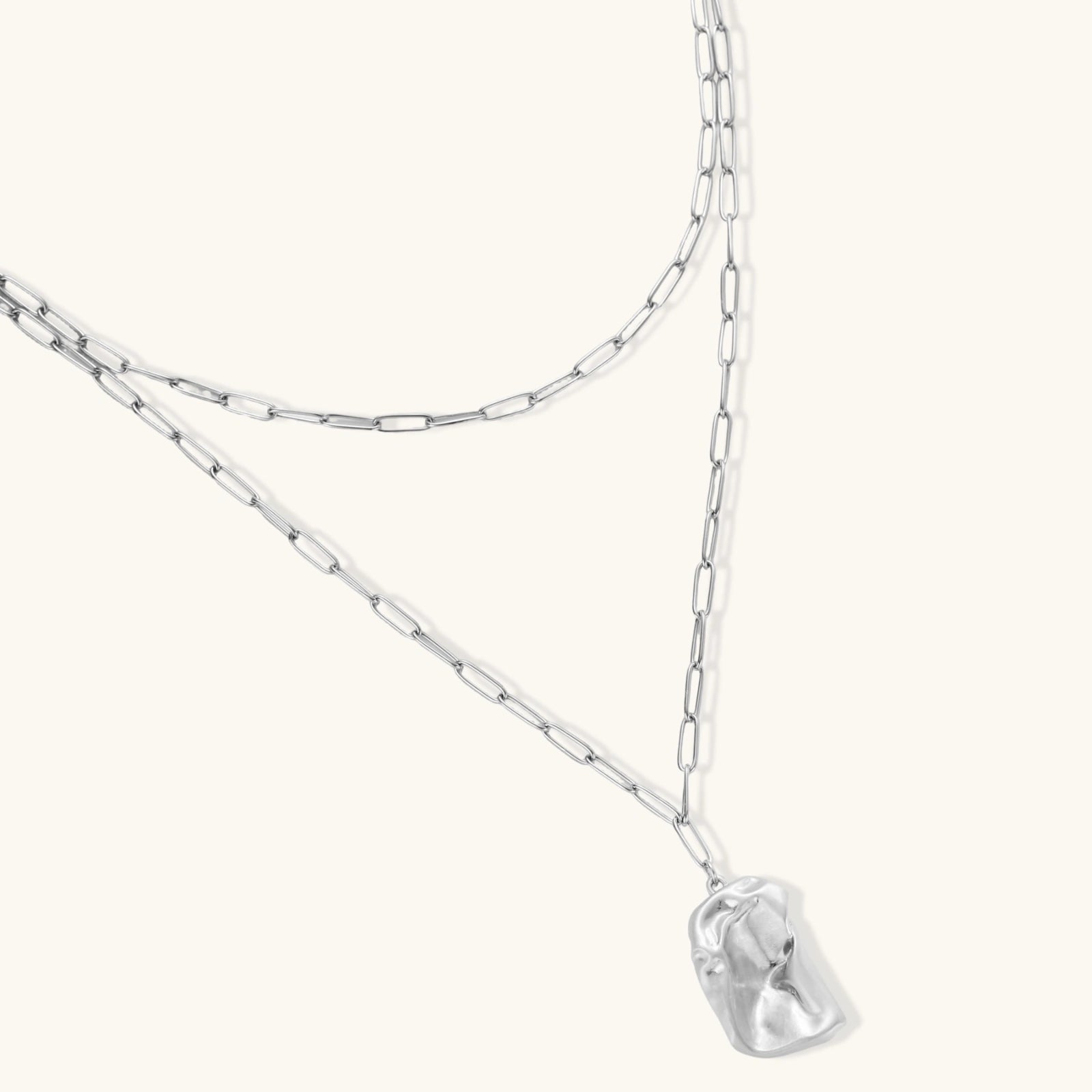Silver necklace with a clear pendant on a white background