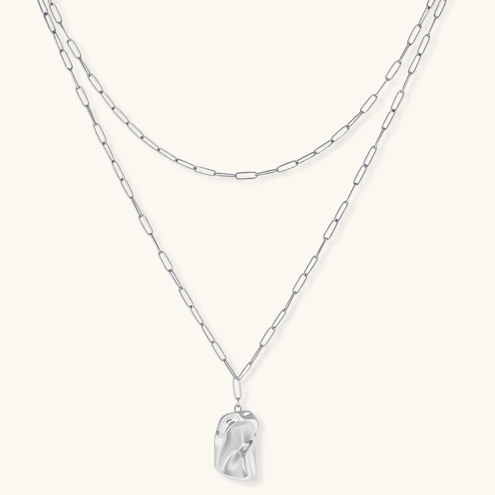 Layered silver chain necklaces with a clear crystal pendant on a white background