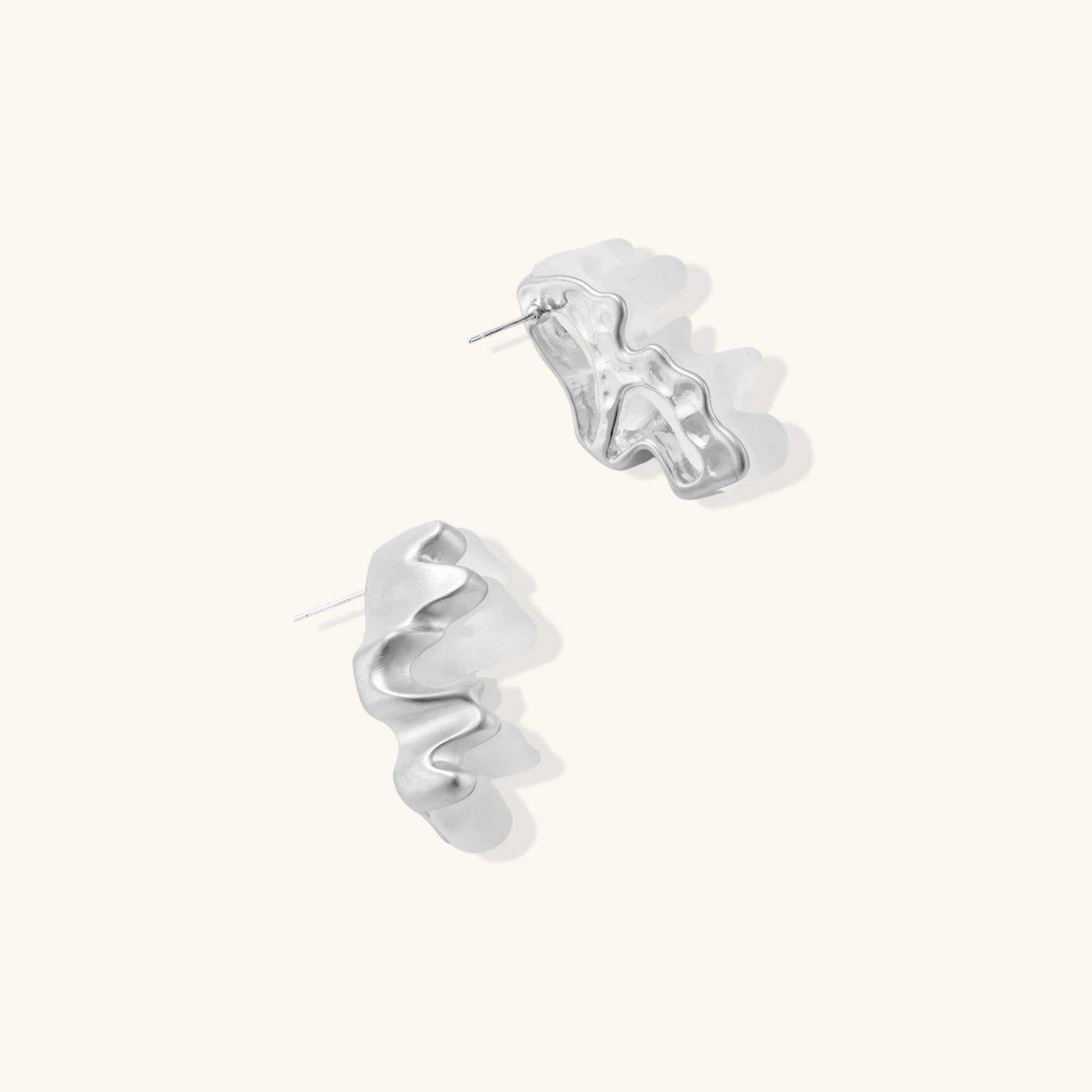 Pair of white spiral hoop earrings on a light beige background