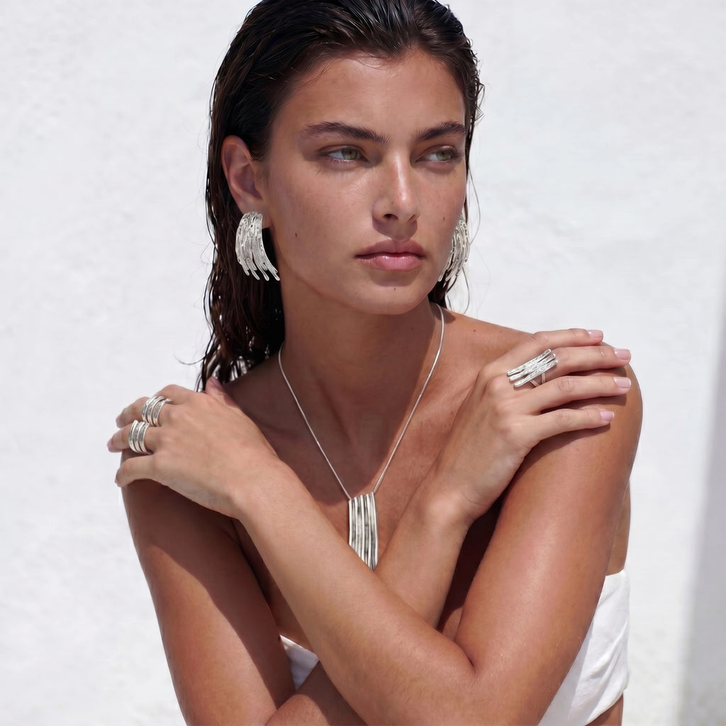 Woman wearing silver statement jewelry against a white background