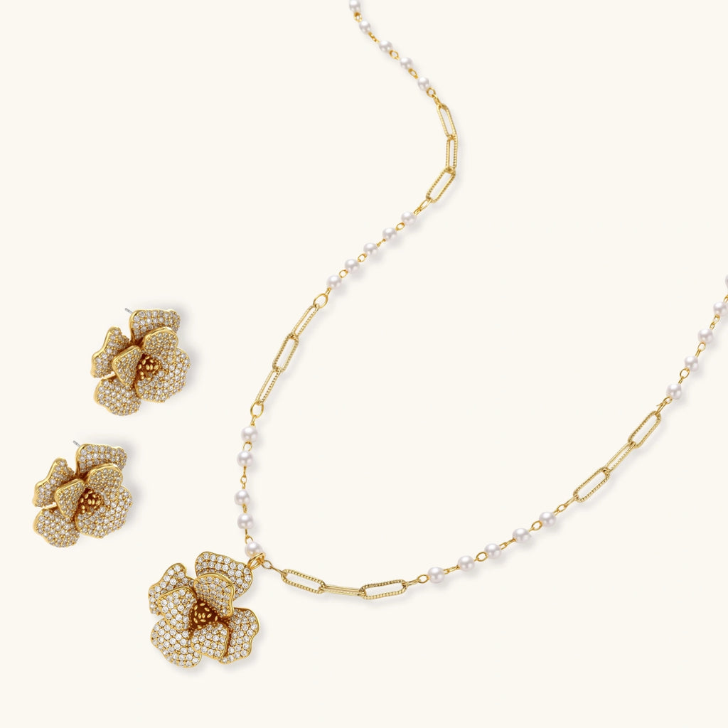 Gold floral necklace and earrings on a white background